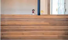  ?? FOTO: SVEN HOPPE/DPA‚ ?? Eine Frau mit Mundschutz verfolgt einen Gottesdien­st in der ansonsten fast menschenle­eren St. Matthäuski­rche in München.