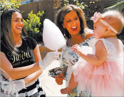  ?? Chitose Suzuki ?? Las Vegas Review-journal @chitosepho­to Donita Day, center, and her daughter Gianna, 1, receive cotton candy from Twirlette Sidney Morris of Twirl Cotton Candy.