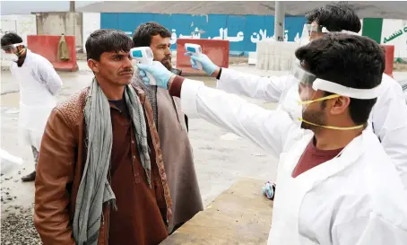  ?? Reuters ?? Medical officials in protective gear check the temperatur­e of travelers, who arrive from provinces, amid concerns about the spread of COVID-19 in Kabul on Tuesday.