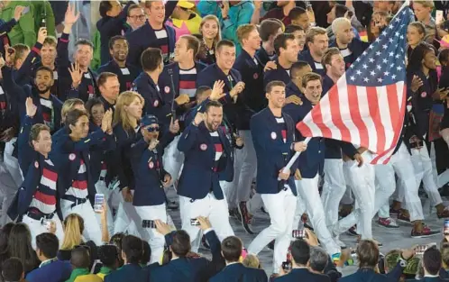  ?? FRANK GUNN/THE CANADIAN PRESS ?? Baltimore swimmer Michael Phelps leads the U.S. team into the opening ceremonies for the 2016 Summer Olympics in Brazil. The NCAA is threatenin­g the end of the United States’ dominance in the Olympic Games if revenue-sport athletes are permitted to earn a share of the millions that their labor generates.