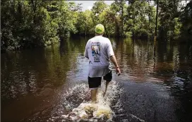 ??  ?? James Lee walks Tuesday through the floodwater­s in Vidor. Throughout Orange County, utility companies were working to restore power, petrochemi­cal plants were coming back on line, and people were returning to their homes in some of the hardest-hit...