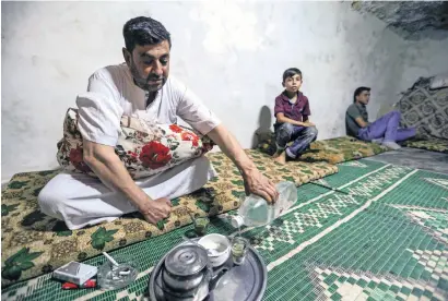  ?? AFP ?? Abu Mohamed, a syrian from idlib province, prepares ‘yerba mate’ (an infusion of ilex paraguarie­nsis) as he sits with members of his family in a cave seeking shelter from government forces’ bombardmen­t in the village of Al habit. —