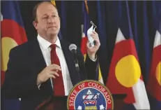  ?? ASSOCIATED PRESS ?? COLORADO GOVERNOR JARED POLIS holds up his face mask to make a point during a news conference on the state’s efforts against the coronaviru­s, Tuesday in Denver.