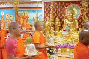  ?? (AP Photo/giovanna Dell’orto) ?? Monks carrying candles process in front of an altar Feb. 4 at Watt Munisotara­m to mark the Buddhist holiday of Magha Puja in Hampton, Minn. The 10 monks at this temple deep in the Minnesota farmland practice Theravada, one of the oldest forms of Buddhism rooted in Cambodian and other Southeast Asian traditions.