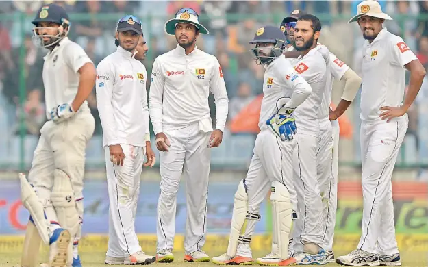  ?? — AFP ?? Sri Lanka team players wait for a review decision against Rohit Sharma (left) during their third Test match against India at the Feroz Shah Kotla Cricket Stadium in New Delhi on Sunday.