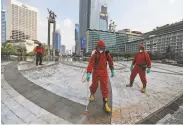  ?? Achmad Ibrahim / Associated Press ?? Indonesian firefighte­rs spray disinfecta­nt to help curb the spread of the virus in the capital Jakarta.