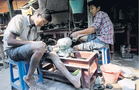 ?? AFP ?? Craftsmen grind stones in their workshop at a wholesale jade market in Mandalay, the second-largest city in Myanmar. The Asian Developmen­t Bank predicts economic growth in Myanmar will surge by more than 8% for the next two years. The bank aims to...