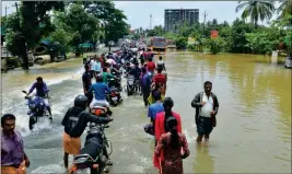  ?? ASSOCIATED PRESS ?? PEOPLE MOVE PAST a flooded road in Thrissur, in the southern Indian state of Kerala, Friday. Rescuers used helicopter­s and boats to evacuate thousands of people stranded on their rooftops following unpreceden­ted flooding in the southern Indian state of Kerala.