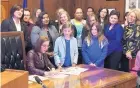  ?? KRISTENA HANSEN/ASSOCIATED PRESS ?? Gov. Kate Brown, seated, signs a bill in Salem, Ore., on Wednesday, making the process more private for transgende­r individual­s to change their birth records.