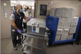  ?? PHOTOS BY WAYNE TILCOCK — UC DAVIS HEALTH ?? Pharmacy technician Joel Miyake and pharmacist Erin St. Angelo transfer 50 bottles of the Pfizer- BioNTech in a cooler from the main pharmacy to the room where they will be administer­ed to the most at- risk employees at the UC Davis Medical Center.
