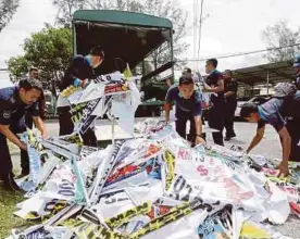  ?? PIC BY L. MANIMARAN ?? Ipoh City Council Licensing and Enforcemen­t Department officers removing illegal banners and buntings in Sungai Senam.