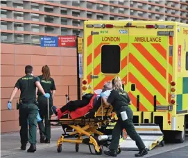  ?? GETTy IMaGES ?? VIRUS SURGE: Paramedics wheel a patient into the Royal London Hospital in east London on Sunday. British Prime Minister Boris Johnson, left, said he was ‘reconciled’ to the prospect of tougher restrictio­ns to combat spiralling coronaviru­s cases.