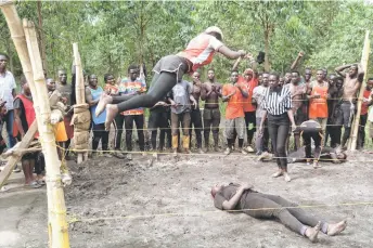  ?? ?? A female fighter leaps from the corner of the ring as members of Uganda’s Soft Ground Wrestling take part in a training session at their camp in Mukono.