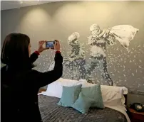  ?? Reuters ?? A visitor takes pictures for graffiti work painted by Banksy in the Walled Off hotel in Bethlehem on Friday. —