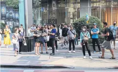  ?? SOMCHAI POOMLARD ?? A guide holds up a flag as a marker for her tourist group to gather around Ratchapras­ong intersecti­on yesterday.