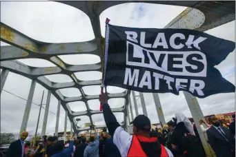  ?? JULIE BENNETT — THE ASSOCIATED PRESS FILE ?? In this file photo, Black Lives Matter demonstrat­or waves a flag on the Edmund Pettus Bridge during the Bloody Sunday commemorat­ion in Selma, Ala.