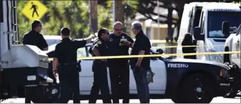  ??  ?? Fresno police officers confer in front of the scene of an officer involved shooting Wednesday. Police say a suspected gang member was shot and killed early Wednesday after he fired a least 75 rounds at officers with a high-powered rifle. Officers were...