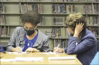  ?? Katie West • Times-Herald ?? Forrest City School Board President Sandra Taylor, left, and superinten­dent Dr. Tiffany Hardrick review paperwork during the special board meeting Monday evening. The board agreed to give employees who receive the Covid vaccine a $200 monthly stipend through April. They also agreed to hire additional staff for the current school year.