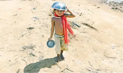  ??  ?? A Rohingya child uses his food bowl to shelter himself from the sun at the Palangkhal­i refugee camp in Ukhia district on Wednesday. (AFP)