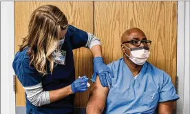  ?? MICHAEL A. MCCOY/ THE NEW YORK TIMES ?? A medical worker receives the PfizerBion­tech COVID- 19 vaccine on Dec. 16 at the Virginia Hospital Center in Arlington, Va.