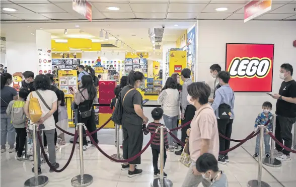  ?? BLOOMBERG ?? Customers line up at an entrance during the opening of a Lego store in Hong Kong on April 29. Lego A/S has said it still plans to open 150 new stores this year, mostly in China.