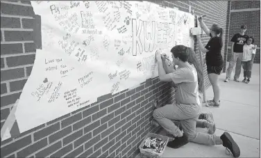  ?? NWA Democrat-Gazette/BEN GOFF • @NWABENGOFF ?? Students and friends write messages on banners and two wooden crosses Sunday during a gathering at Jarrell Williams Bulldog Stadium in Springdale to remember Springdale senior Kyler Williams. Friends, family and students from Springdale High and other...