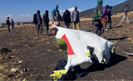  ?? Reuters ?? People walk past a part of the wreckage at the scene of the Ethiopian plane crash, near the town of Bishoftu, southeast of Addis Ababa, on Sunday. —