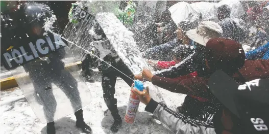  ?? JUAN CARLOS CISNEROS/AFP VIA GETTY IMAGES FILES ?? People marching in honour of those who died during clashes with police during demonstrat­ions against Peruvian President Dina Boluarte, stop and spray police with foam and water as a carnival tradition in Puno, Peru.