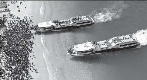  ?? MELISSA DELPORT / @TRUFFLEJOU­RNAL VIA REUTERS ?? Boats arrive at shore to evacuate people on the island of Gili Trawangan, Lombok, Indonesia, on Monday. This still image is taken from a drone video obtained from social