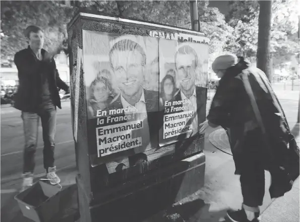  ?? JACQUES DEMARTHON / AFP / GETTY IMAGES ?? Supporters put up posters for French presidenti­al election candidate Emmanuel Macron on Friday in Paris.