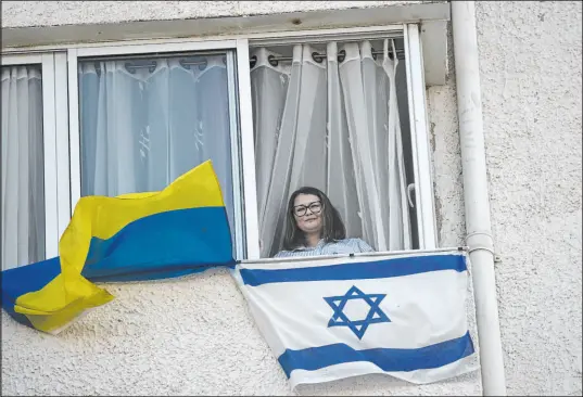  ?? Maya Alleruzzo The Associated Press ?? Tatyana Prima, who fled Mariupol, Ukraine, with her national flag and the Israeli flag outside her window in Ashkelon, Israel.