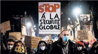  ?? LIONEL BONAVENTUR­E/GETTY-AFP ?? A protester holds a placard reading “stop to the global security law” as he takes part in a rally Thursday in Toulouse, France. The new bill would restrict the filming of police officers.