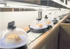  ??  ?? Plates of sushi covered with domes move along a conveyor belt at a Kura Corp restaurant in Kaizuka in Osaka prefecture.