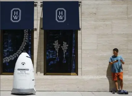  ?? MICHAEL CIAGLO, THE ASSOCIATED PRESS ?? A new security robot, nicknamed ROD2, drives toward Daniel Webb as it patrols the sidewalks and parking garage at River Oaks District in Houston.