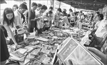  ??  ?? Browsing at a book stall displaying books on Myanmar history in Yangon.