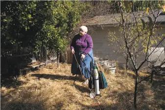  ?? Rachel Bujalski / Special to The Chronicle ?? Leslie Smyth, 77, who resorted to a portable oxygen tank when she couldn’t use her electric oxygen concentrat­or, checks a cord connecting her refrigerat­or to her neighbor’s generator.