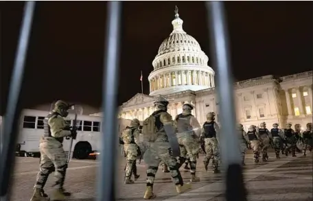  ?? Jacquelyn Martin Associated Press ?? ITS NEOCLASSIC­AL lines aglow, the U. S. Capitol towers above National Guard members arriving to help secure it Wednesday night.