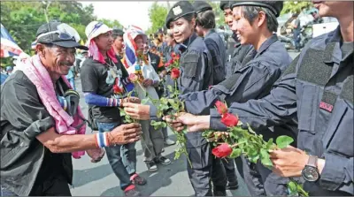  ?? CHRISTOPHE ARCHAMBAUL­T / AGENCE FRANCE-PRESSE ?? Thai anti-government protesters greet and receive flowers from police after protesters crossed barricades in Bangkok on Tuesday.