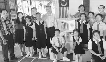  ??  ?? Lo (fourth left, back row) with teachers and students at the SJK Chung Hua Stampin school library.