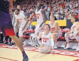  ?? ROBERTO E. ROSALES/JOURNAL ?? UNM’s Dane Kuiper falls after hitting a 3-pointer from the corner while teammates watch from the Lobos’ bench. Arizona had a strong first half and coasted to an 89-73 win on Saturday.