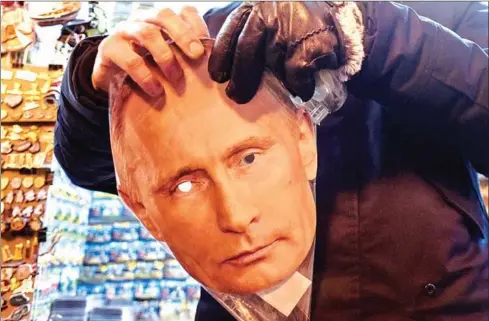  ?? AFP ?? A mask of Russian President Vladimir Putin is seen on sale among other items at a souvenir stall in Saint Petersburg.