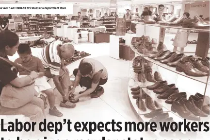  ??  ?? A SALES ATTENDANT fits shoes at a department store.
