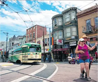  ?? JUSTIN FRANZ/THE WASHINGTON POST ?? A streetcar painted in vintage green and cream livery passes people square dancing in the famous Castro District of San Francisco.