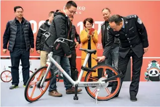  ?? Cnsphoto ?? 26 de febrero de 2017. Tan Qiao, célebre oficial de tránsito de Chengdu (Sichuan), desencaden­a la bicicleta Mobike No. 100.000 de su ciudad.