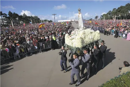  ?? Armando Franca / Associated Press ?? A statue of the Virgin Mary is carried by faithful before the start of Pope Francis’ canonizati­on Mass in Fatima, Portugal.