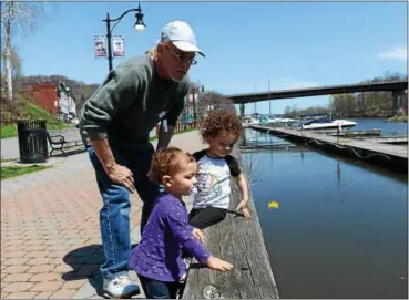  ?? TANIA BARRICKLO — DAILY FREEMAN ?? Taking advantage of Tuesday’s pleasant weather, 15-month-old Mercedes Girard, foreground, daughter of Malinda Williamson of Kingston, throws a dandelion into the Rondout Creek while visiting the city waterfront with her sister, Angelese Girard, 2, and...