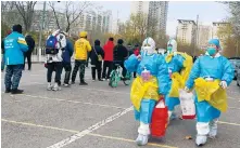  ?? Photo: Simon Song ?? Health workers walk past people waiting to get tested in Beijing.