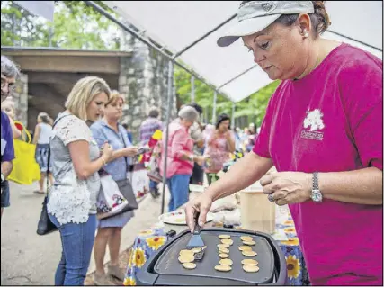 ?? JONATHAN PHILLIPS PHOTOS / SPECIAL ?? Sheree Elliott flips tiny pancakes as she makes samples for people to taste during last year’s Yellow Daisy Festival at Stone Mountain Park. The festival features more than 400 artists from all over the country over four days.