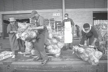  ??  ?? Chefs with Compassion volunteers Zizwe Kheswa (centre left), Donald Maike (centre right) load in a pick-up truck a pallet containing discarded cabbages to be rescued at the City Deep Fresh Product Market in Johannesbu­rg.