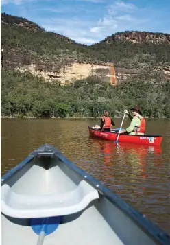  ??  ?? After rain, waterfalls spill over the towering sandstone cliffs and down into Lake Yarrunga below.